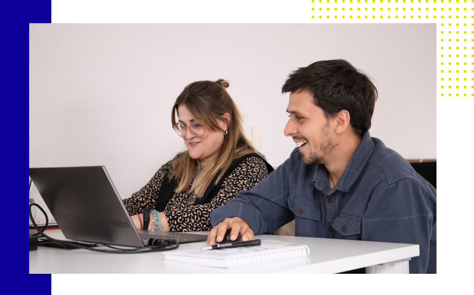 Dos personas trabajando en equipo y sonriendo.